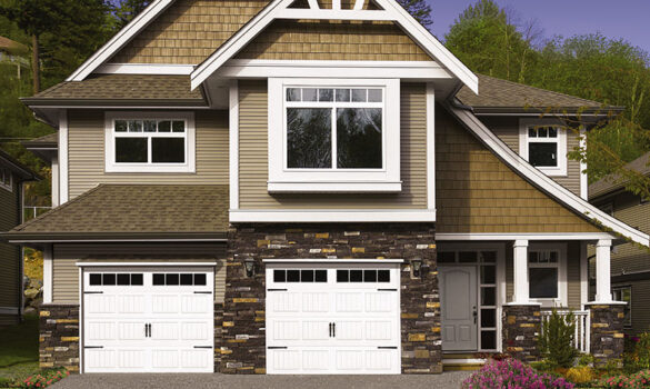 A large home with brown siding and two white garage doors.